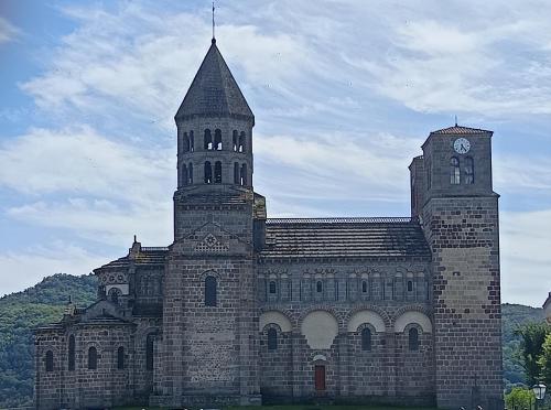 a large stone building with a clock tower at Le Nid du Haut in Saint-Nectaire