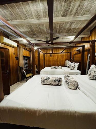 two beds in a room with wooden walls at Cara Galle Fort in Galle