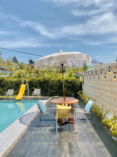 a table with an umbrella next to a pool at Villa Tiella By The Villas 100 in Bogor