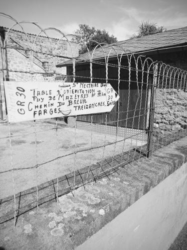 a fence with signs on it next to a building at L'Echappée Romane in Saint-Nectaire