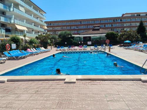 a large swimming pool with people swimming in it at Alegre apto con piscina, a 300m de la playa. in Blanes