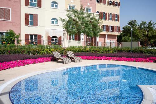 a swimming pool with two chairs next to a building at Luxury studio in Discovery Gardens near metro in Dubai