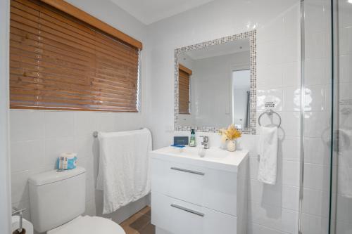 een badkamer met een toilet, een wastafel en een spiegel bij Waterfront holiday home in Banksia Beach