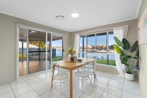 a dining room with a table and chairs and windows at Waterfront holiday home in Banksia Beach