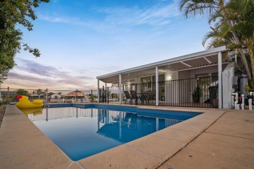 a swimming pool in front of a house at Waterfront holiday home in Banksia Beach