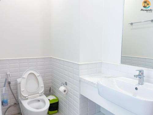 a white bathroom with a toilet and a sink at Sunset town Phú Quốc in Phu Quoc