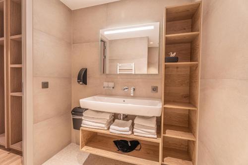 a bathroom with a sink and a mirror and towels at Strandhotel Duinoord in Vrouwenpolder