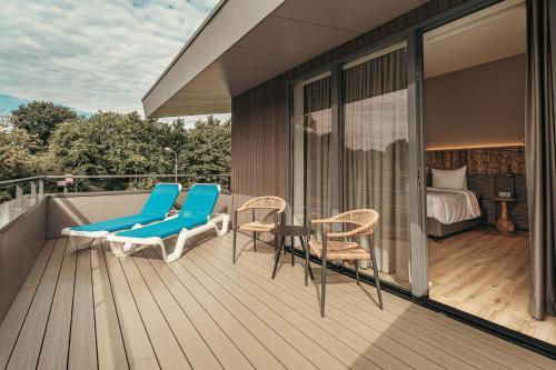 a balcony with chairs and a table and a bed at Strandhotel Duinoord in Vrouwenpolder