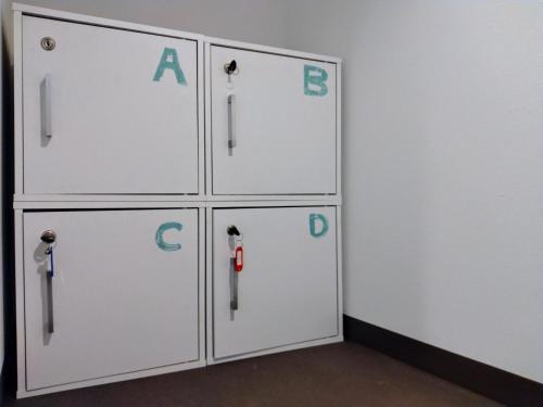 a row of white lockers with letters on them at TONARINO Hostel for Backpackers in Kobe