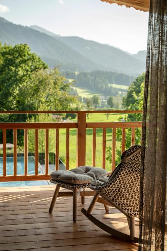 a wicker chair sitting on a deck with a view at Kaiserlodge in Scheffau am Wilden Kaiser