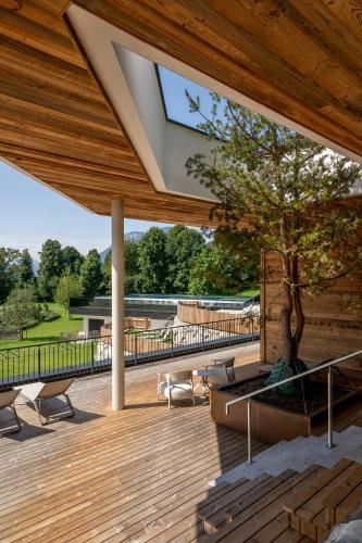a wooden deck with a tree and a building at Kaiserlodge in Scheffau am Wilden Kaiser