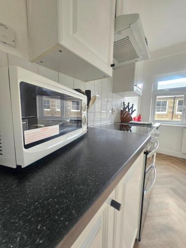 a kitchen with a microwave above a black counter top at Riviera Loft Penzance in Penzance