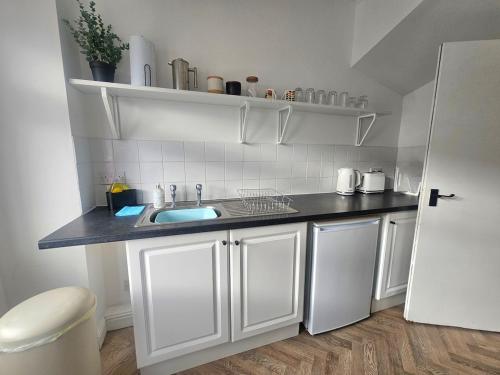 a white kitchen with a sink and a white refrigerator at Riviera Loft Penzance in Penzance