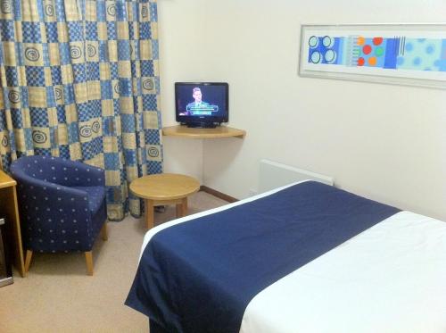 a bedroom with a bed and a chair and a television at Days Inn by Wyndham Telford Ironbridge in Telford