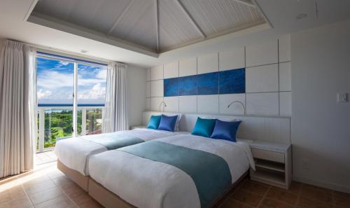 une chambre avec un grand lit avec des oreillers bleus dans l'établissement The Shigira, à Île Miyako