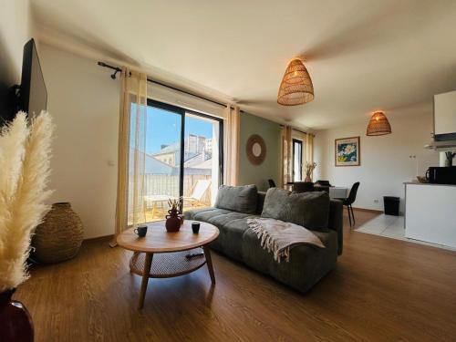 een woonkamer met een bank en een tafel bij Casa Arcade Rougé - Premium - Terrasse - Parking in Cholet