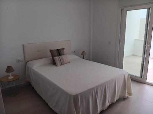 a white bedroom with a bed and a large window at Arenas de Plata Atlanterra in Zahara de los Atunes