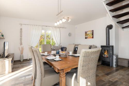 a dining room with a wooden table and a fireplace at Haus Storchennest in Dranske