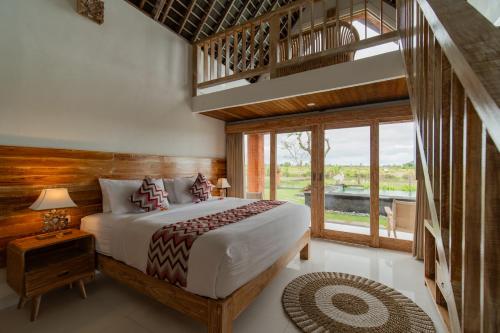 a bedroom with a bed and a large window at Dewi Sri Villa in Ubud