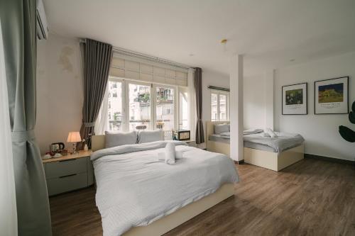 a white bedroom with two beds and a window at Chez Lumi Hotel in Hanoi