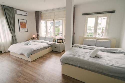 two beds in a bedroom with two windows at Chez Lumi Hotel in Hanoi