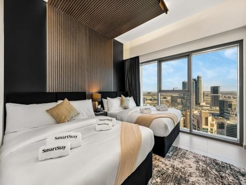 two beds in a hotel room with a large window at SmartStay at Burj Royale - Unique Downtown Dubai City Views - Brand New Luxury Apartments in Dubai