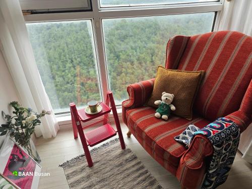 a teddy bear sitting in a chair in front of a window at Baan Busan - 3mins to Haeundae Beach in Busan