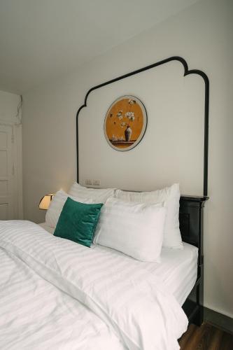 a bed with white pillows and a clock on the wall at Chez Lumi Hotel in Hanoi