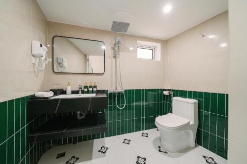 a green and white bathroom with a toilet and a sink at Chez Lumi Hotel in Hanoi