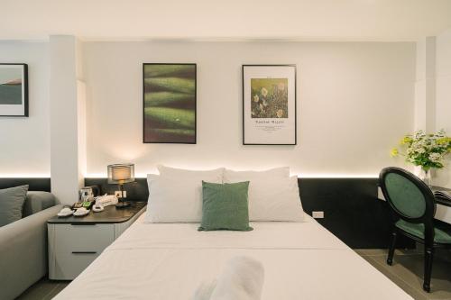 a bedroom with a white bed with a desk and a couch at Chez Lumi Hotel in Hanoi