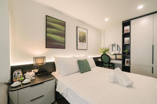 a bedroom with a white bed and a desk with a lamp at Chez Lumi Hotel in Hanoi