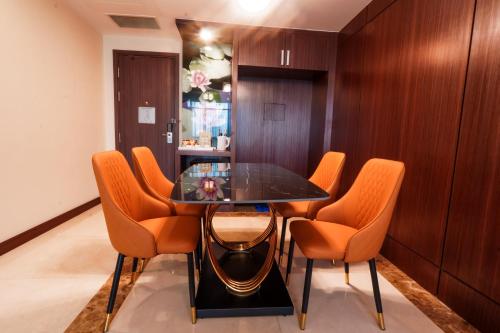 a dining room with a glass table and orange chairs at Becamex Hotel New City in Thu Dau Mot