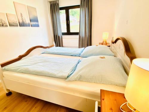 a bedroom with a bed with blue sheets and a window at Ferienwohnung Marlene 80 Qm in Ebersburg
