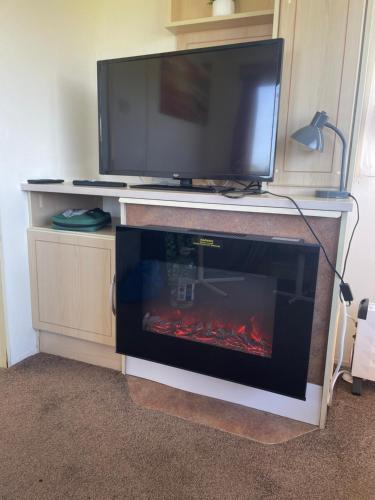 a tv and a fireplace with a fire in it at Kernow Wishes in Newquay