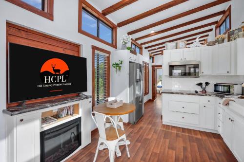 a kitchen with white cabinets and a flat screen tv at ShenanigInn at Bent Tree Ranch in Lampasas