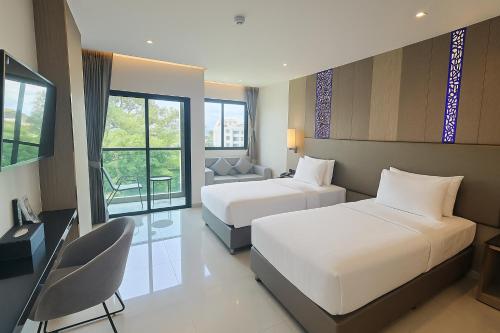 a hotel room with two beds and a chair at THE TJ HOTEL Pattaya in Jomtien Beach