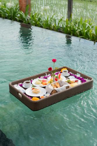 un vassoio di cibo sopra un tavolo nell'acqua di Dewi Sri Villa by Mahaputra ad Ubud