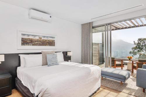 a bedroom with a white bed and a large window at Clouds Estate in Stellenbosch