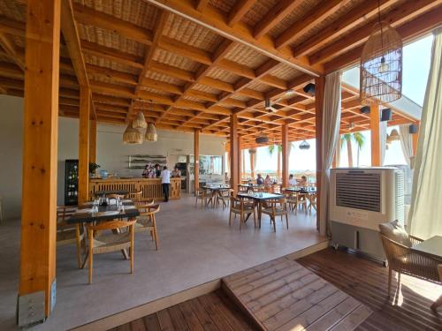 ルコヴァにあるNalu Beach Villasの木製の天井とテーブルと椅子のあるレストラン
