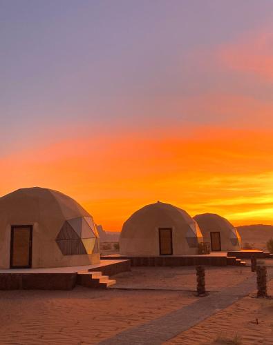 three domes in the desert with a sunset in the background at Wadi Rum, Hala bubbles in Wadi Rum