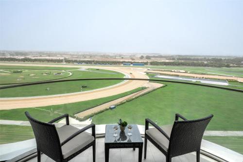 a balcony with two chairs and a table and a race track at The Meydan Hotel Dubai in Dubai