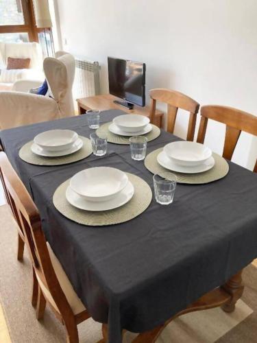 a dining room table with plates and glasses on it at Apartamento Tarmañones Vistas a la montaña in Escarrilla