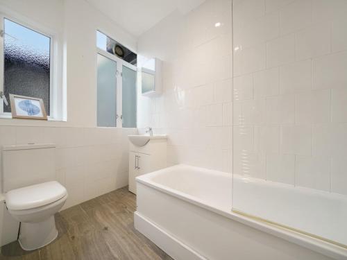 a white bathroom with a tub and a toilet at Pass the Keys Cosy apartment in Kilburn in London
