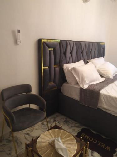 a bedroom with a bed and a chair and a table at chambre meublée Douala Cameroun, bonapriso, eau chaude, wifi haut débit, clim, gardien in Douala