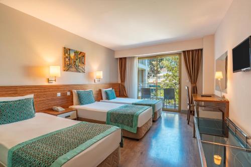 a hotel room with two beds and a television at Tu Casa Gelidonya Hotel in Kemer