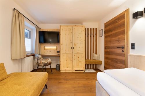a living room with a wooden door and a kitchen at Hotel Garni Landhaus Platzer in Zell am Ziller