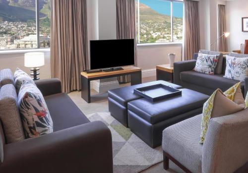 a living room with couches and a flat screen tv at Southern Sun Cape Sun in Cape Town