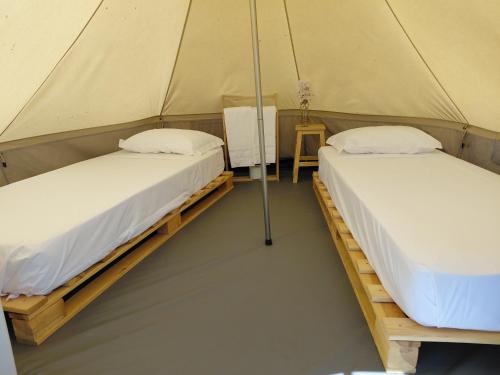 two beds in a tent with a table at Orla Ilha de Tavira Eco-Glamping in Tavira