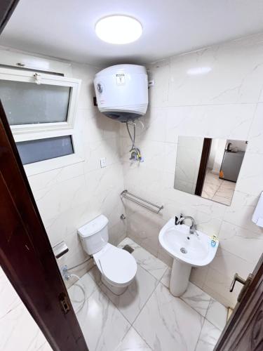 a white bathroom with a toilet and a sink at Hi pyramids view in Banī Ghālib