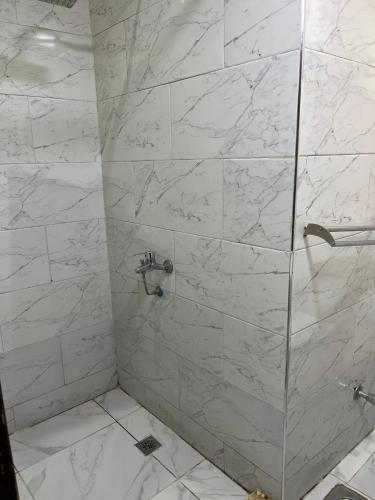 a bathroom with a shower with white marble tiles at Hi pyramids view in Banī Ghālib